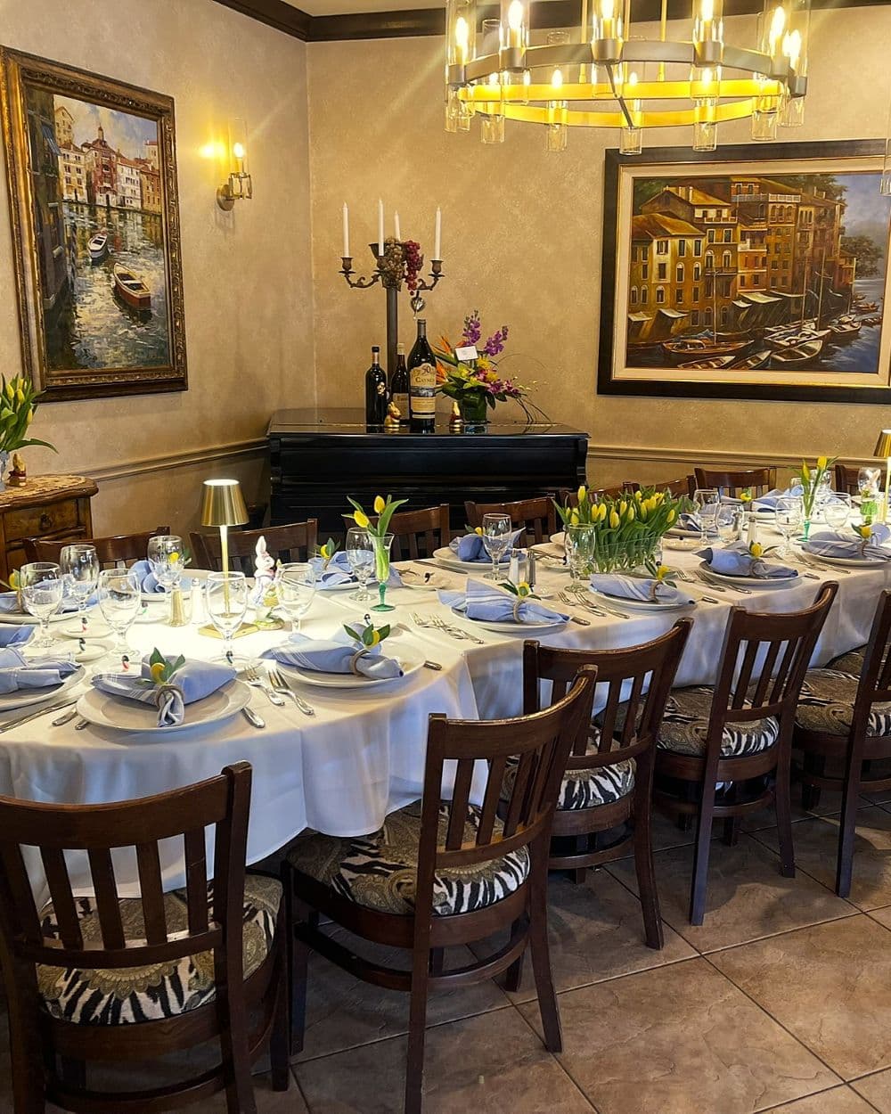 Formal dinner with yellow tulip centerpieces, white tablecloth, and Italian artwork