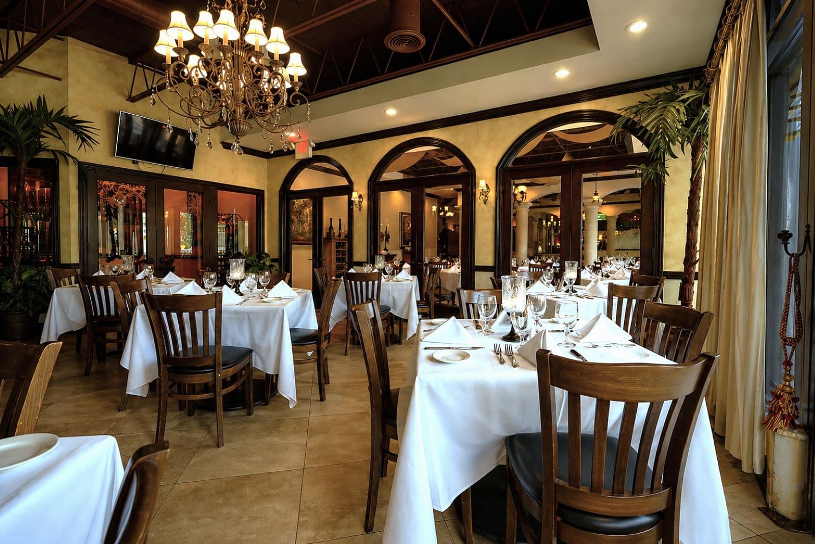 Private dining room at Josephine's with Tuscan arched doorways, wrought-iron chandelier and elegantly set white-tablecloth tables