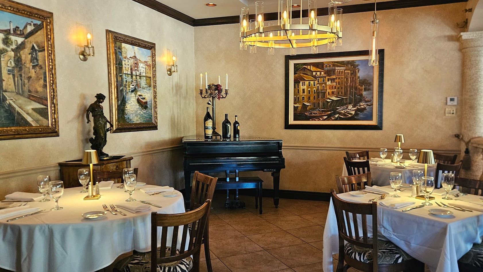Semi-private dining room at Josephine's with round tables, grand piano, Italian artwork and pendant chandeliers