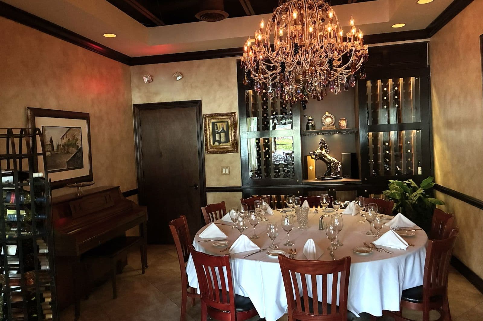 Private wine room at Josephine's with backlit wine display cabinet, ornate chandelier and intimate round table setting
